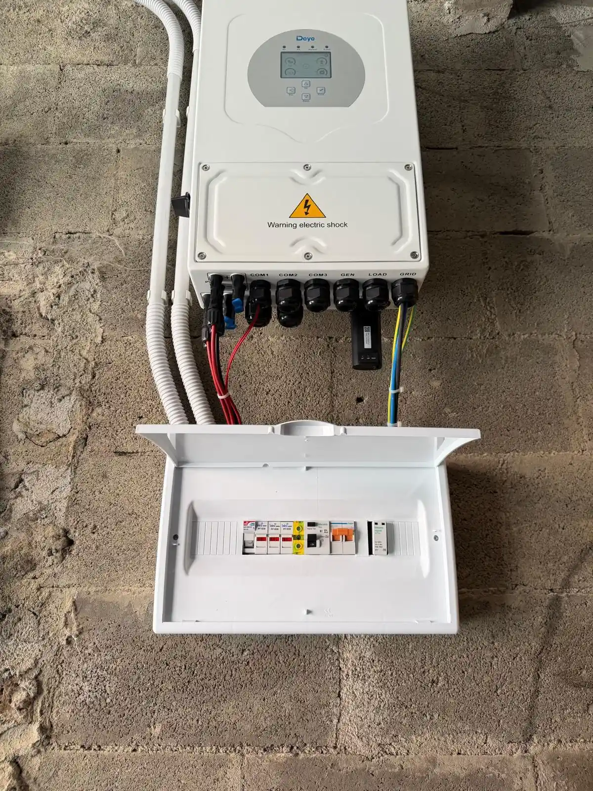 Instalación de paneles fotovoltaicos con inversor híbrido blanco y cableado protegido en Getafe